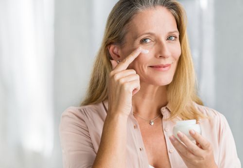Middle aged woman going through her skin care routine, applying a lotion or cream